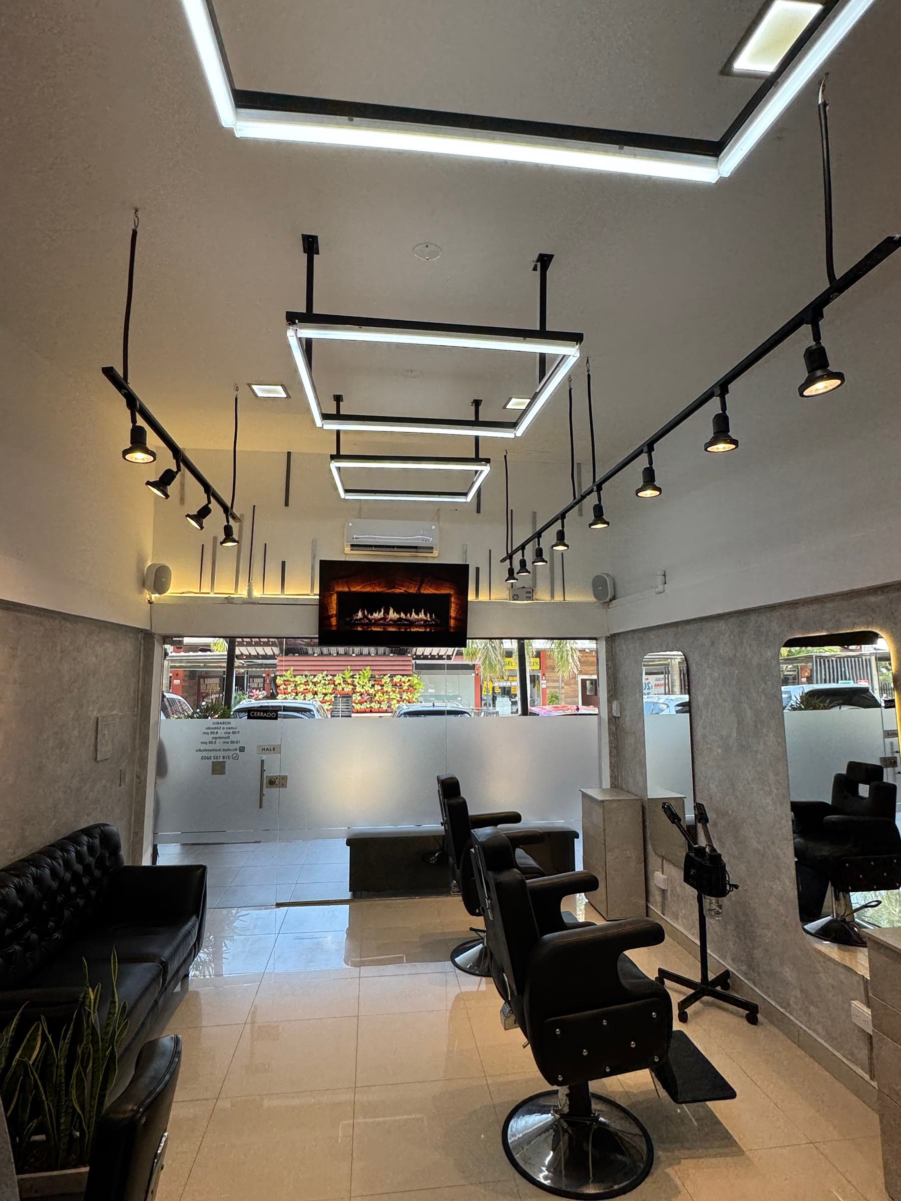 Interior del estudio con sillones de barbero, espejos y luces colgantes